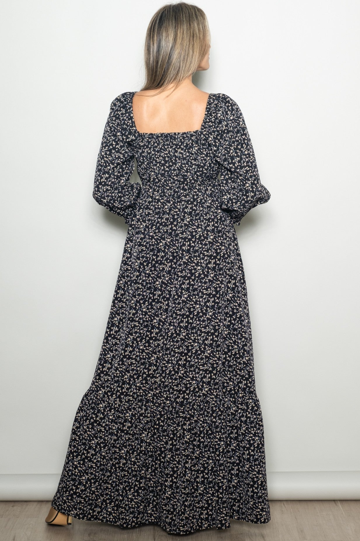 woman wearing a long black floral maxi dress with puffed sleeves and a square back view