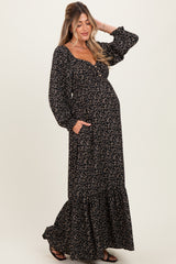 woman wearing a black floral maternity maxi dress with long sleeves and pockets, showing her baby bump
