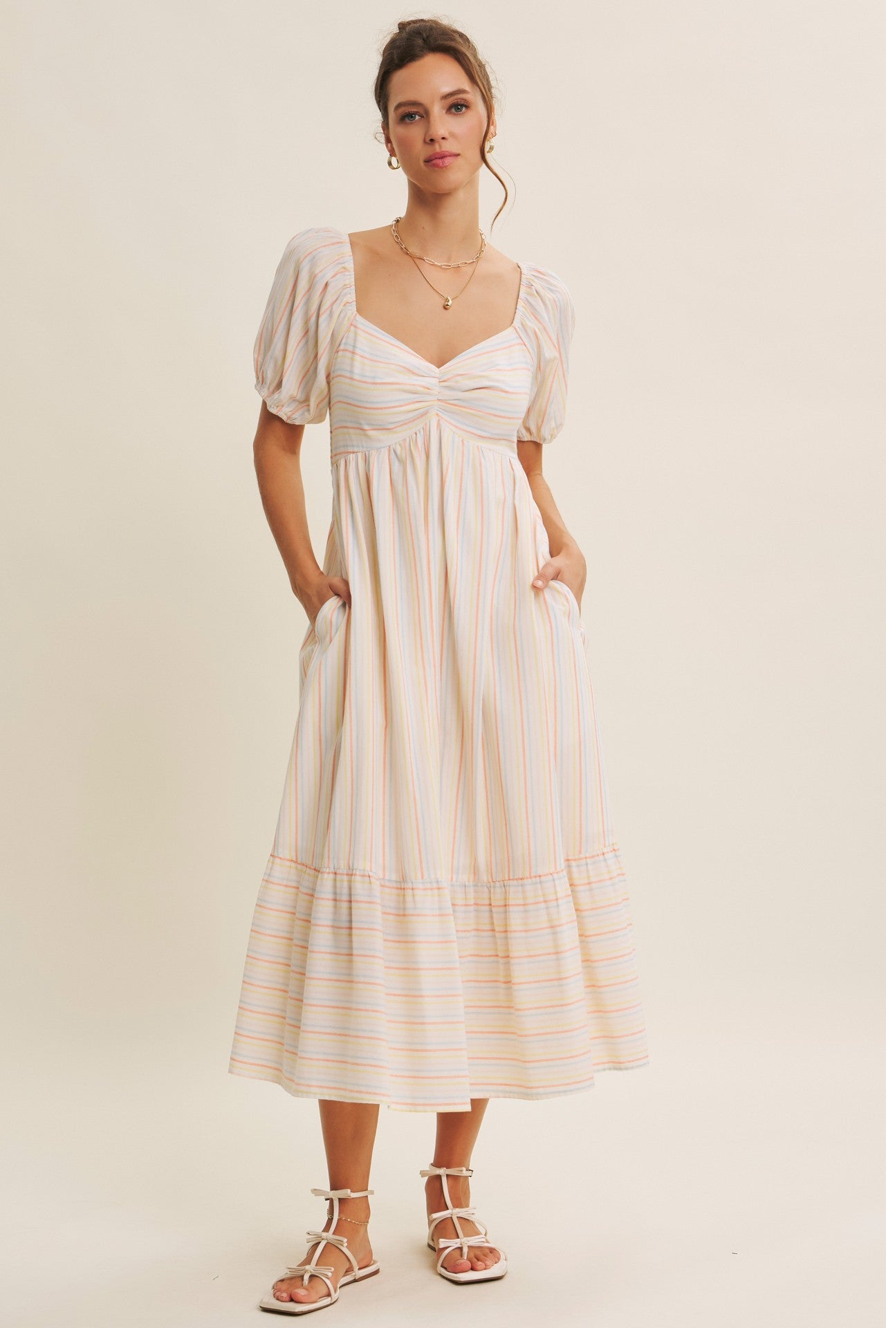 woman wearing a striped midi dress with puff sleeves and a tiered hem, featuring pockets and a flattering neckline