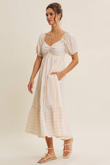 woman wearing a striped midi dress with puff sleeves and a sweetheart neckline, featuring side pockets and a tiered hemline