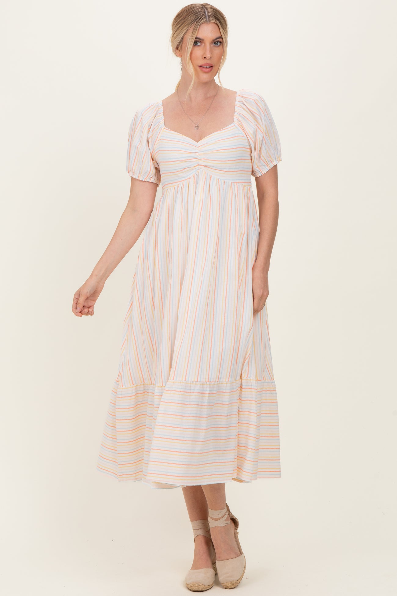 woman wearing a white striped maxi dress with puff sleeves and a tiered hemline