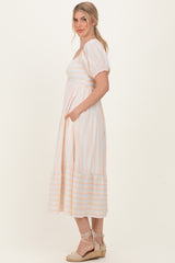 woman wearing a striped midi dress with short puff sleeves and pockets, styled with espadrille sandals