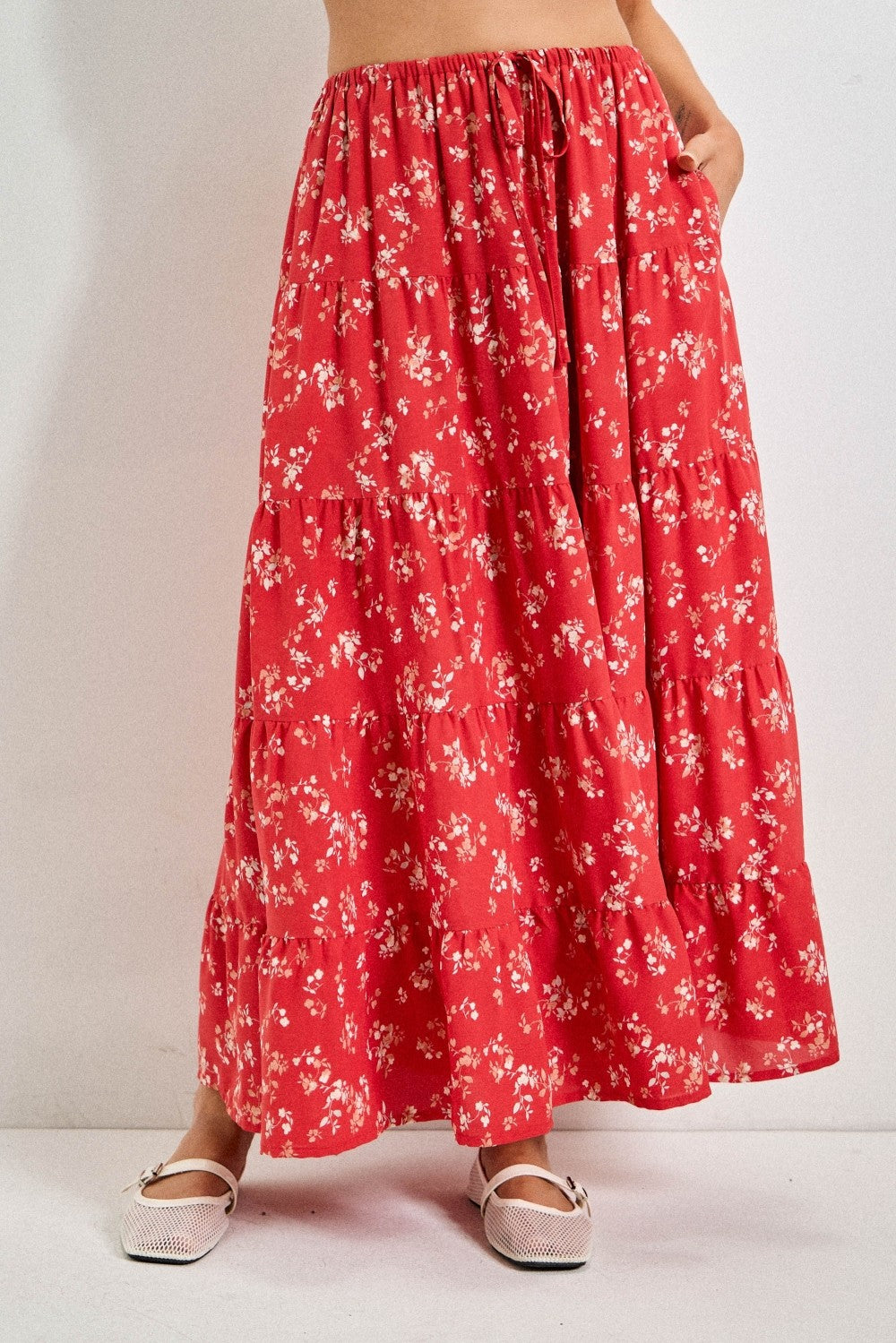 woman wearing a red floral maxi skirt with tiered layers and pockets
