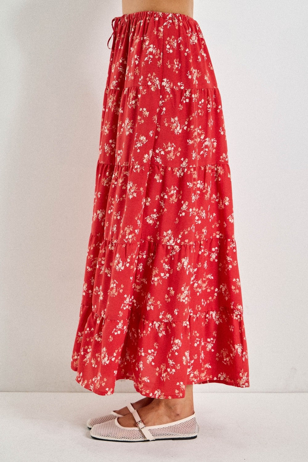 woman wearing a red floral tiered maxi skirt with an elastic drawstring waist and white flats