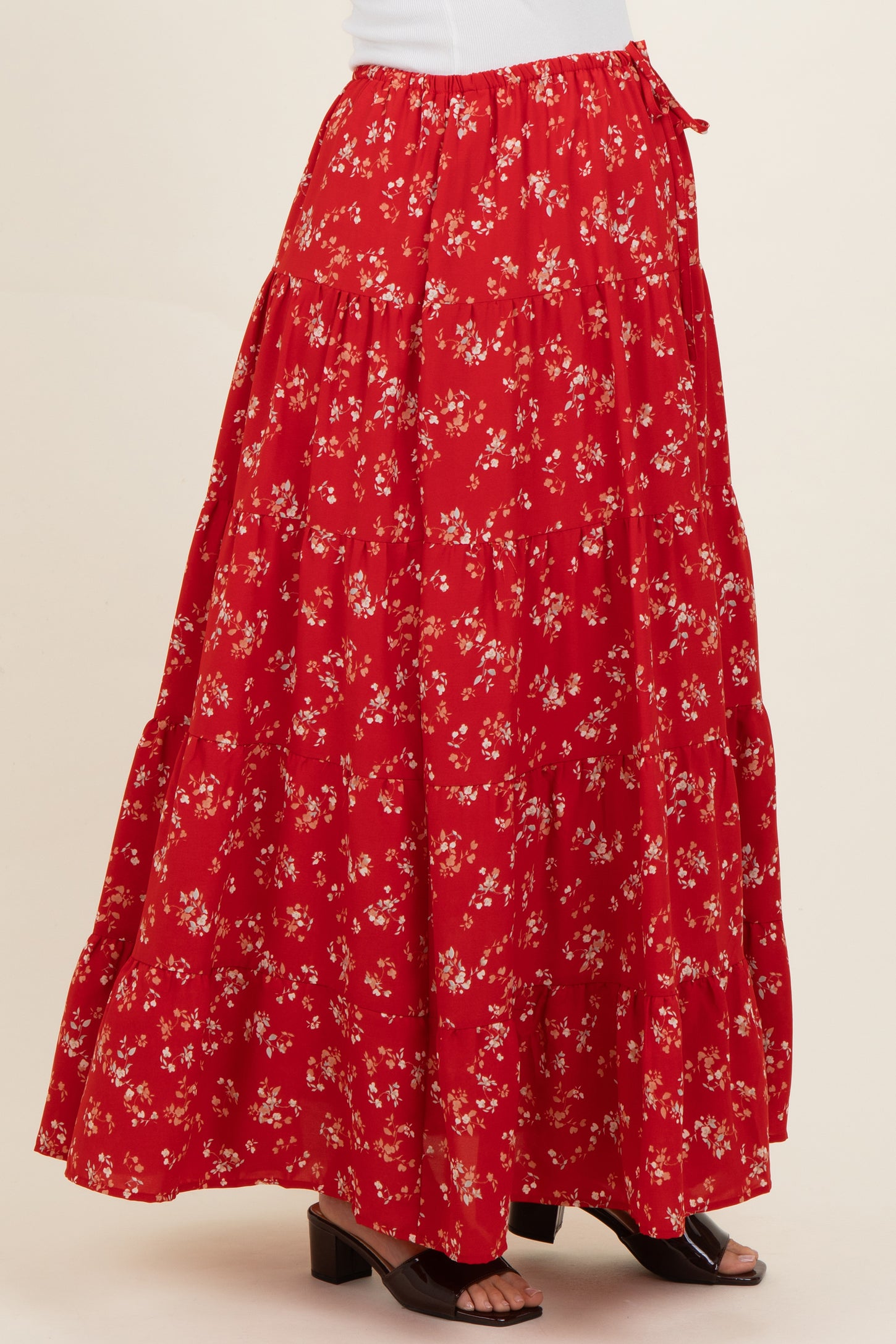woman wearing a red floral maternity maxi skirt with a tiered design and side tie detail