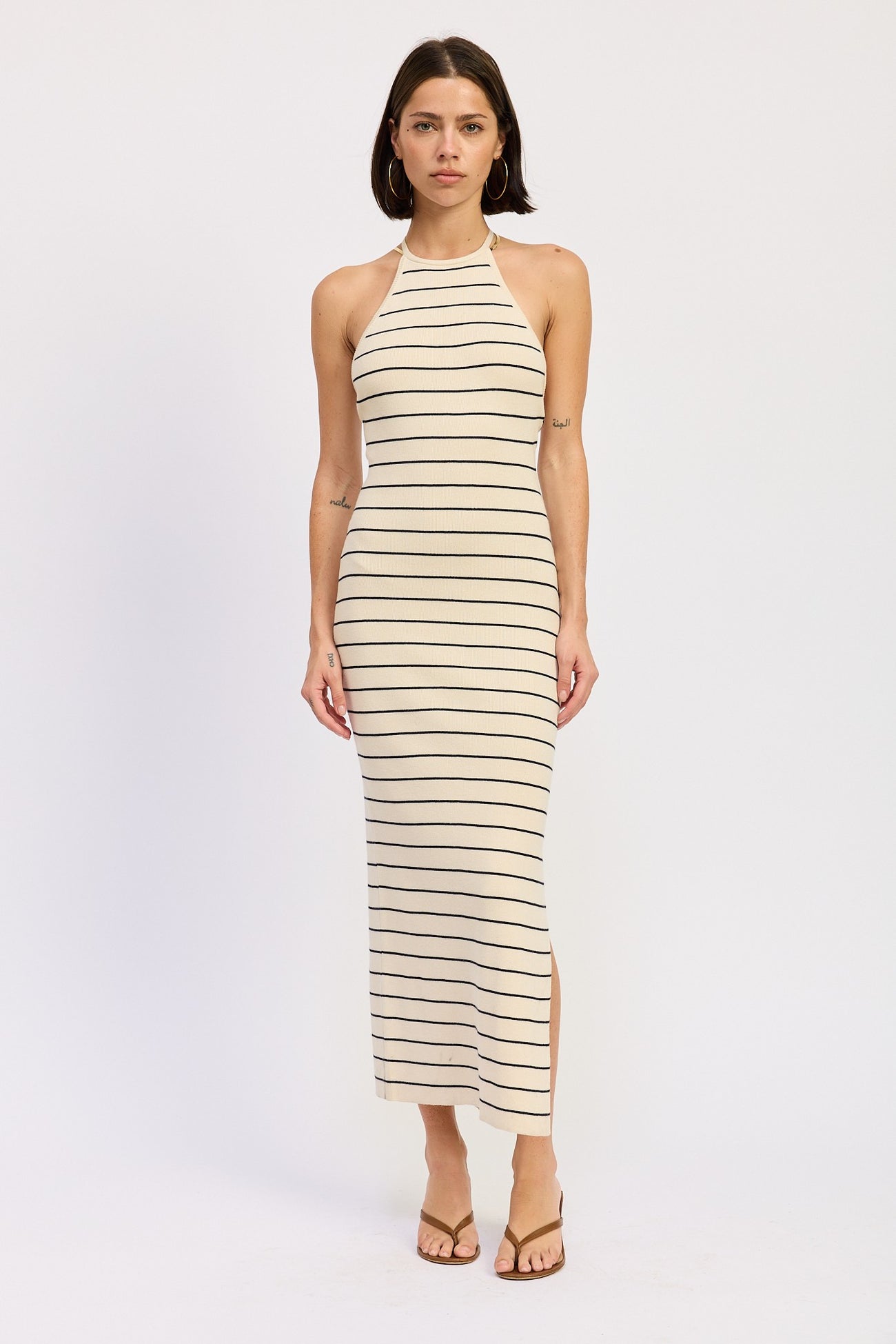 woman wearing a beige striped halter neck maxi dress with side slits