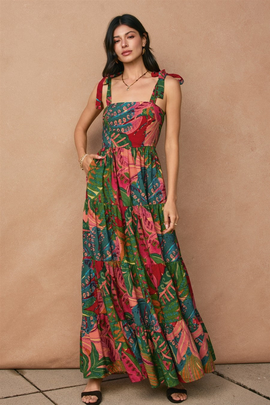 woman wearing a colorful floral maxi dress with tie straps and a tiered skirt