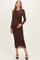 woman wearing a brown floral lace maternity dress with long sleeves and a fitted silhouette, showing her baby bump