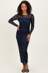 woman wearing a navy long sleeve evening dress with black floral lace details and ruched design