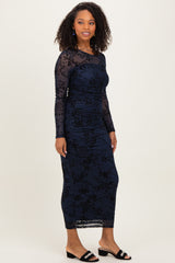 woman wearing a navy blue long sleeve dress with floral lace overlay and ruched detailing, styled with black slide sandals
