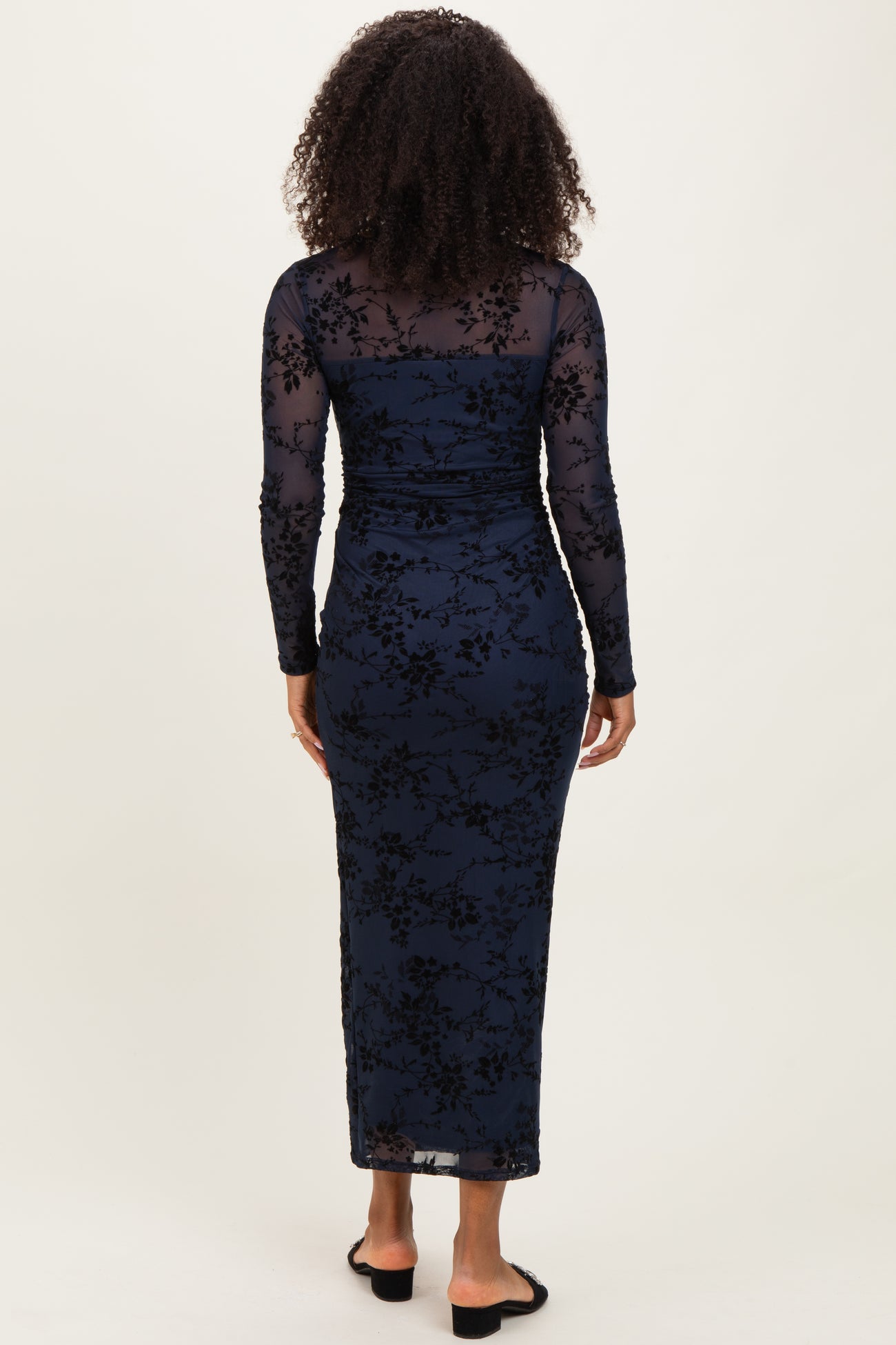 woman wearing a navy blue long sleeve floral lace dress with a fitted silhouette and a floor-length hem