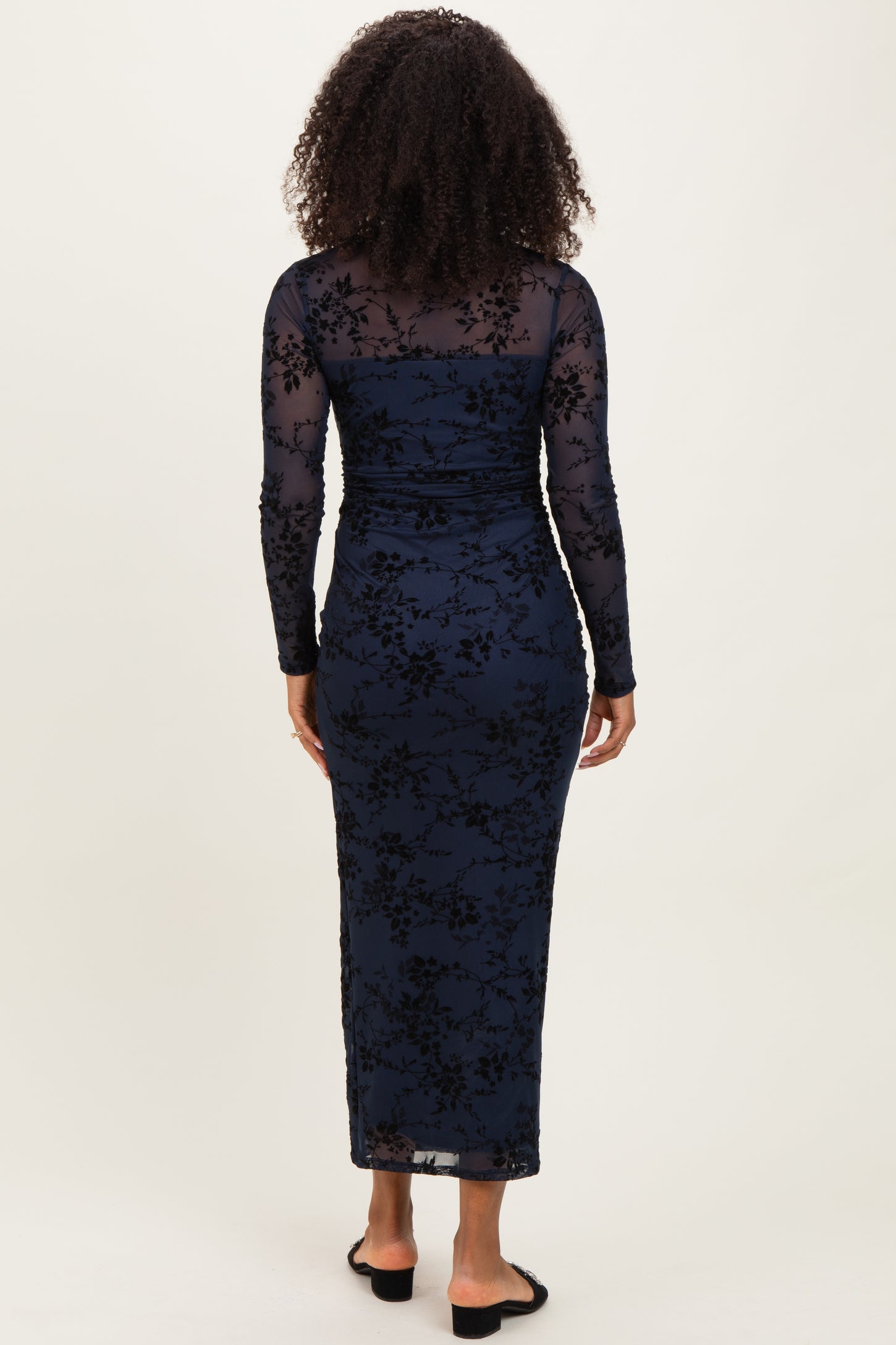 woman wearing a navy blue long sleeve floral lace dress with a fitted silhouette and a floor-length hem