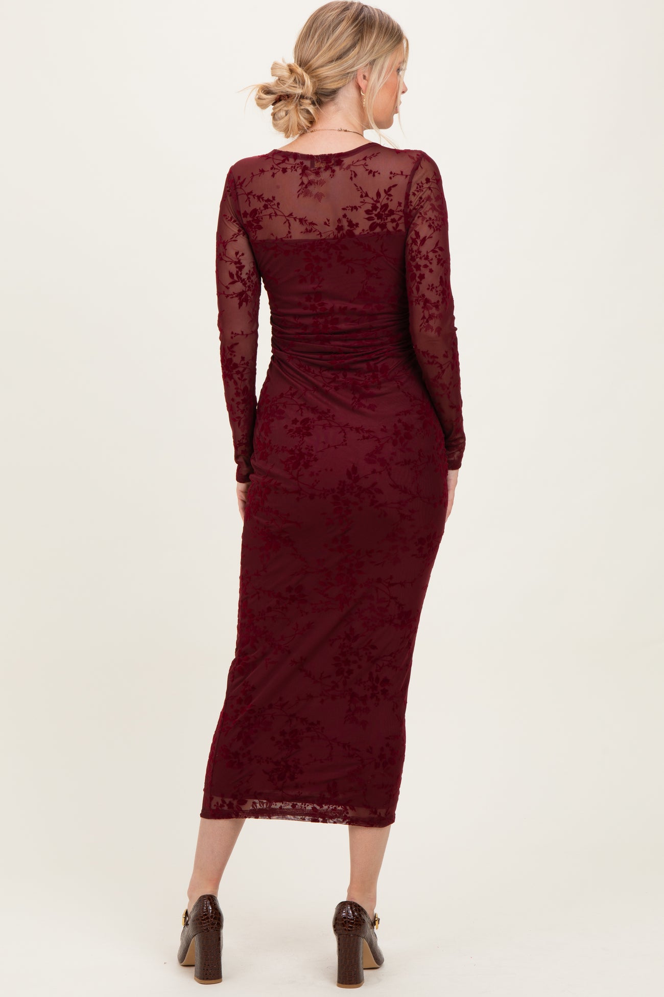 woman wearing a burgundy long sleeve lace dress with a fitted silhouette and mid-calf length, viewed from the back