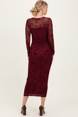 woman wearing a burgundy long sleeve lace dress with a fitted silhouette and mid-calf length, viewed from the back
