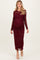 woman wearing a burgundy long sleeve maternity dress with floral lace overlay and a visible baby bump