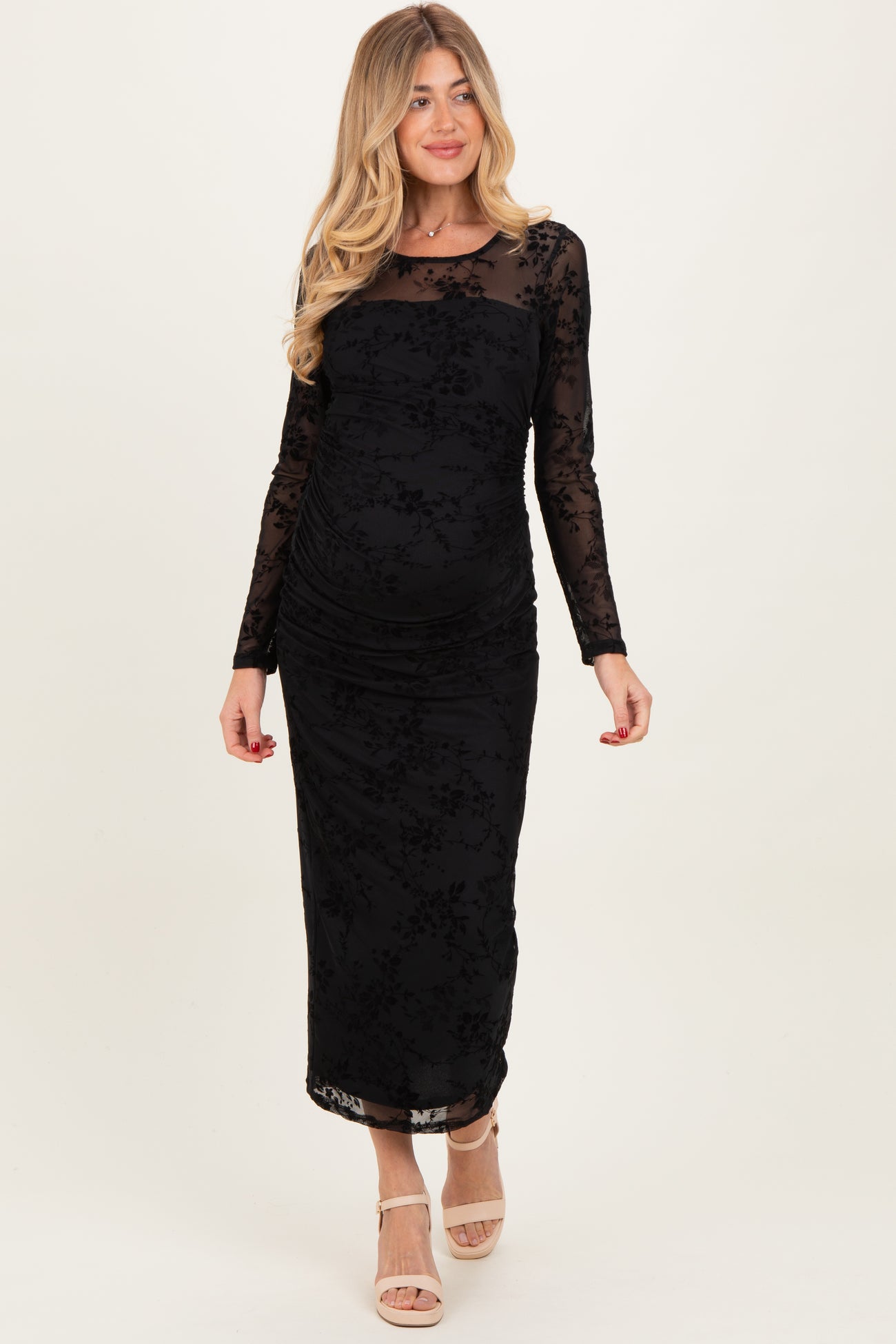 woman wearing a black long sleeve maternity dress with floral patterns and ruching on the sides, showing her baby bump