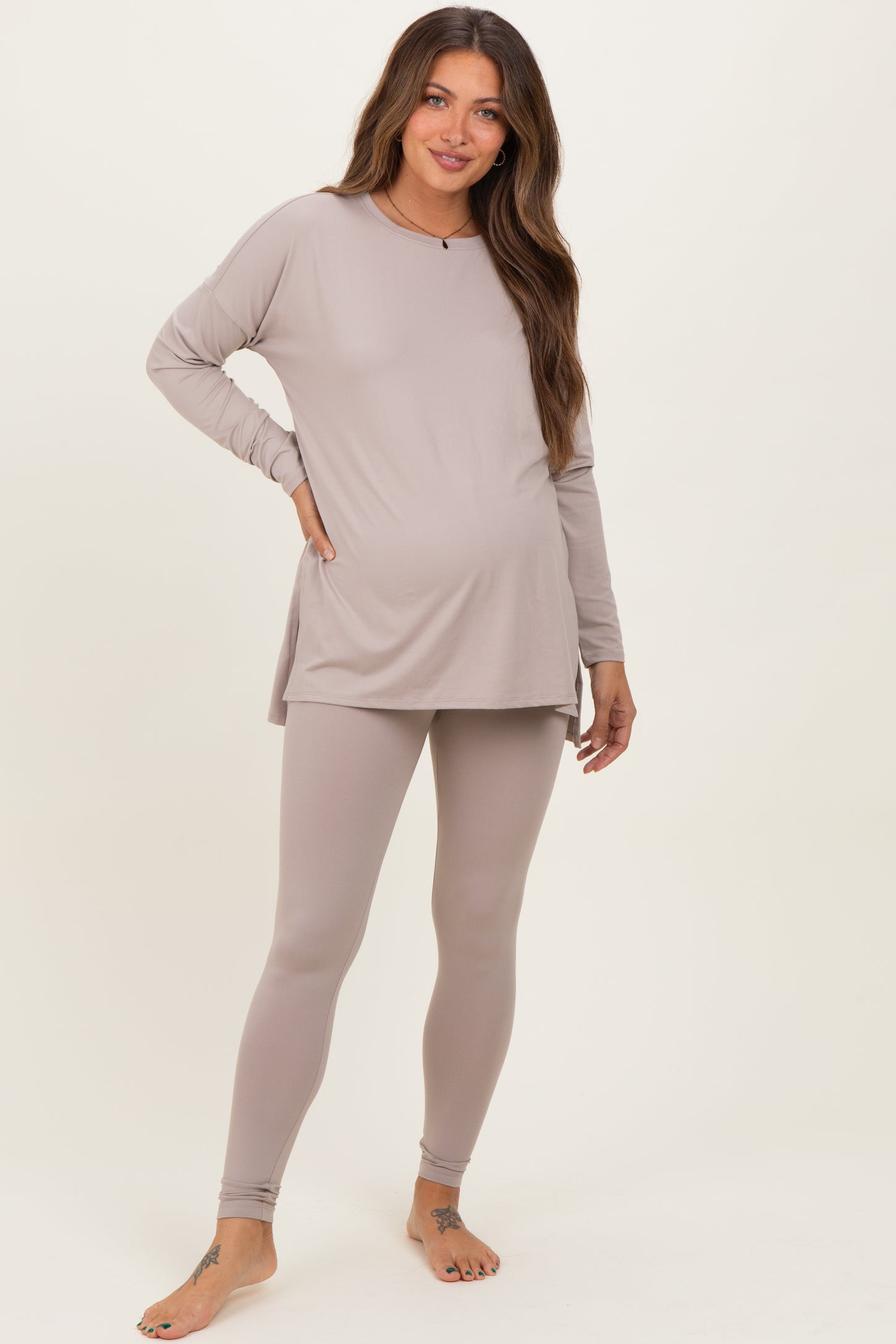 woman wearing a light taupe long sleeve maternity top and matching leggings, showing her baby bump