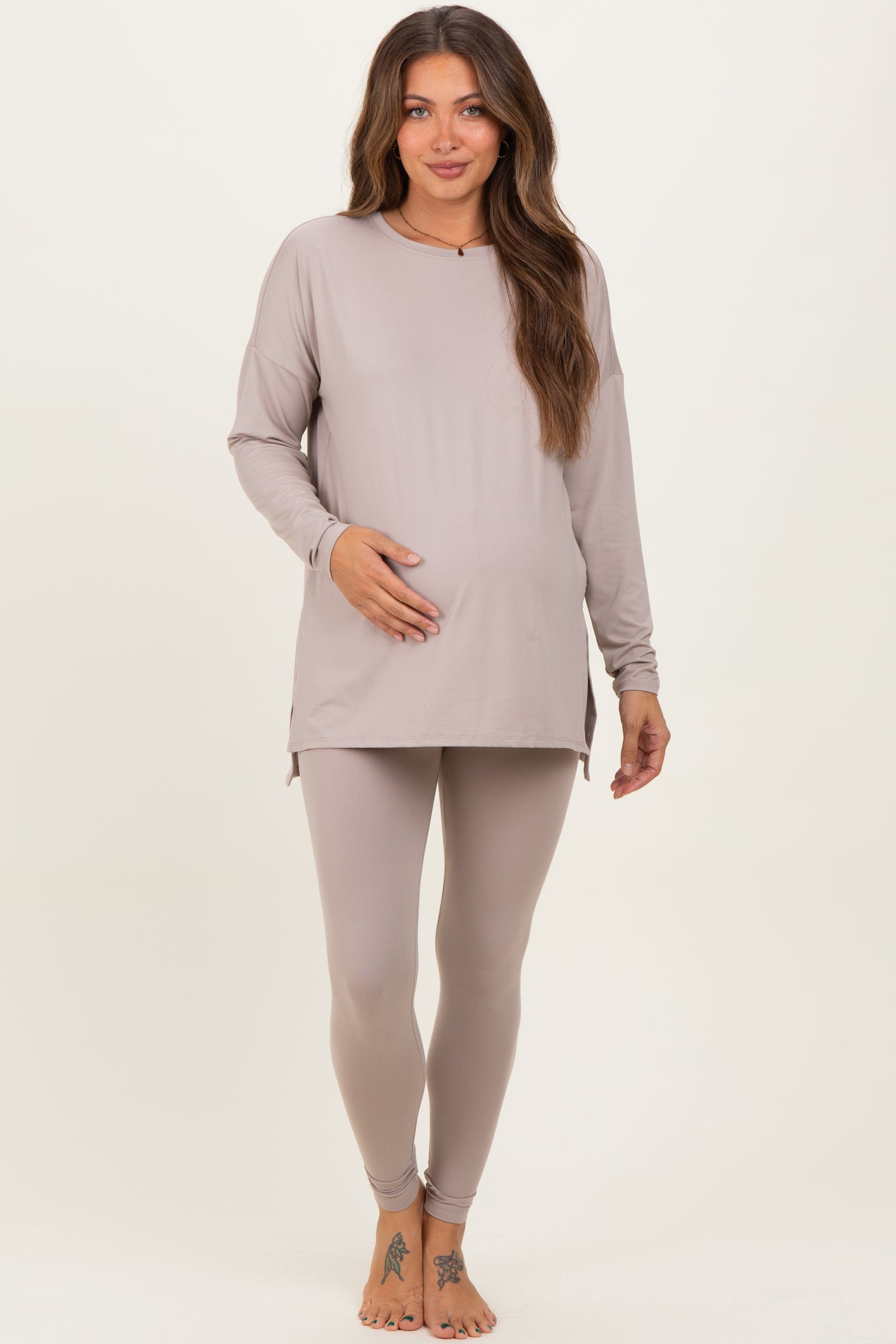 woman wearing a light taupe long sleeve maternity top and matching leggings, showing her baby bump