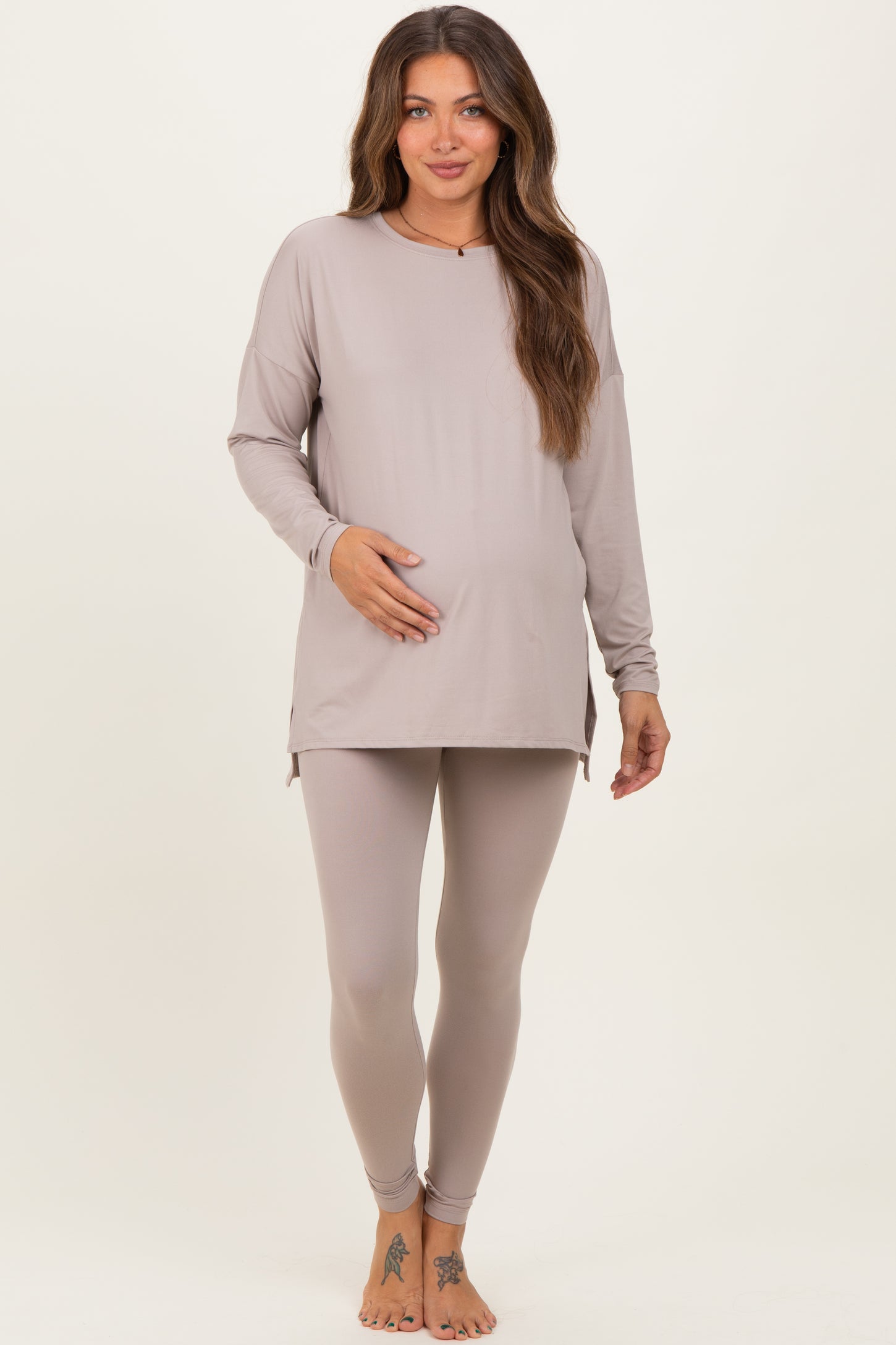 woman wearing a light taupe long sleeve maternity top and matching leggings, showing her baby bump