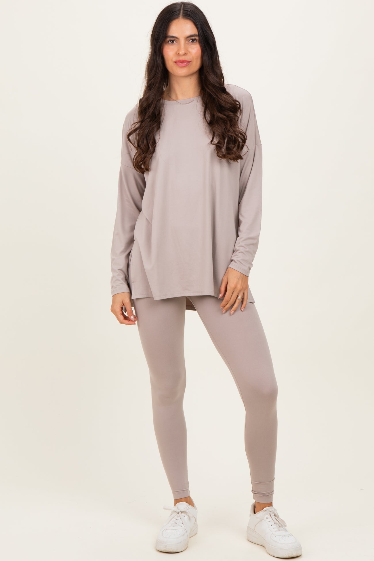 woman wearing a light taupe long sleeve top and matching leggings with white sneakers