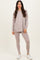 woman wearing a light taupe long sleeve top and matching leggings with white sneakers