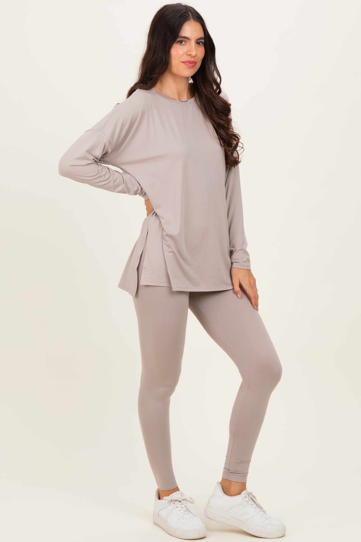 woman wearing a light taupe long sleeve top with side slits and matching leggings, styled with white sneakers