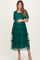 woman wearing a dark green maternity dress with tiered tulle layers and short flutter sleeves, holding her baby bump