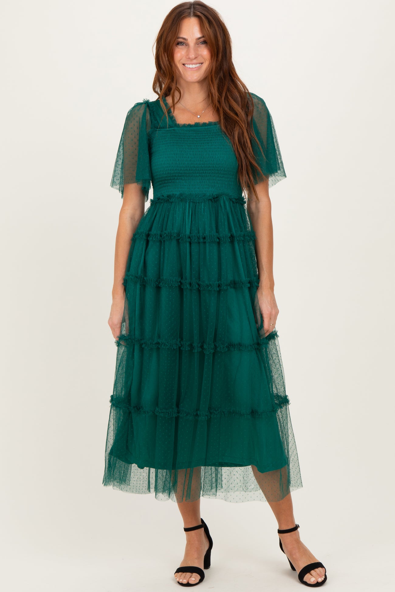 woman wearing a green tiered midi dress with short sleeves and a smocked bodice, styled with black strappy heels