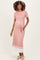 woman wearing a pink ribbed maternity dress with a belted waist and pleated hem, showcasing her baby bump