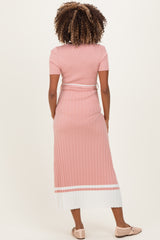 woman wearing a light pink ribbed maternity dress with short sleeves and a white striped hem