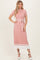 woman wearing a pink ribbed midi dress with a white tie waist and contrasting hem details, standing against a neutral background