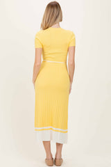 woman wearing a yellow ribbed midi dress with short sleeves and white stripe detail at the hem, showing the back view