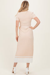 woman wearing a light pink ribbed two-piece set with a short sleeve top and a midi skirt, view from the back