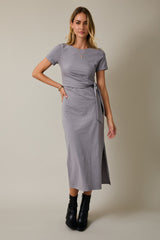 woman wearing a grey wrap dress with short sleeves and a side slit, styled with black ankle boots