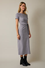 woman wearing a gray short sleeve wrap tie dress with a midi length and black ankle boots