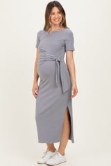 woman wearing a gray maternity maxi dress with a tie waist and side slit, showing off her baby bump