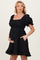 woman wearing a black puff sleeve maternity dress with a cinched waist and pockets, showing her baby bump