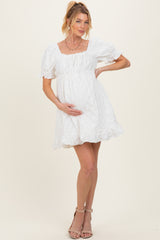 woman wearing a white puff sleeve maternity dress and cradling her baby bump