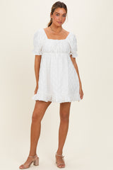 woman wearing a white short puff sleeve dress with a square neckline and ruffled hem