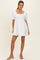 woman wearing a white short puff sleeve dress with a square neckline and ruffled hem