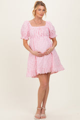 woman wearing a pink puff sleeve maternity dress and holding her baby bump