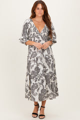 woman wearing a black and white paisley print maxi dress with a deep v-neck and tiered skirt