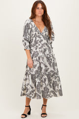 woman wearing a black and white patterned long sleeve midi dress with a v-neckline and tiered skirt.