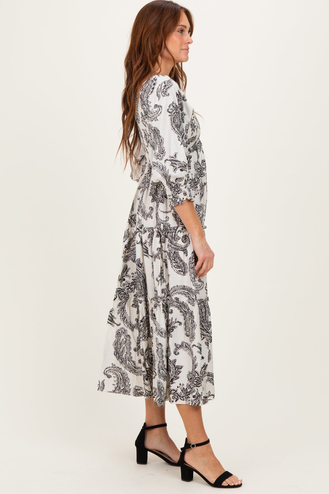 woman wearing a black and white paisley print midi dress with flutter sleeves and a flowing silhouette