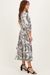 woman wearing a black and white paisley print midi dress with flutter sleeves and a flowing silhouette