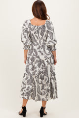 woman wearing a black and white patterned midi dress with puff sleeves and a tiered skirt
