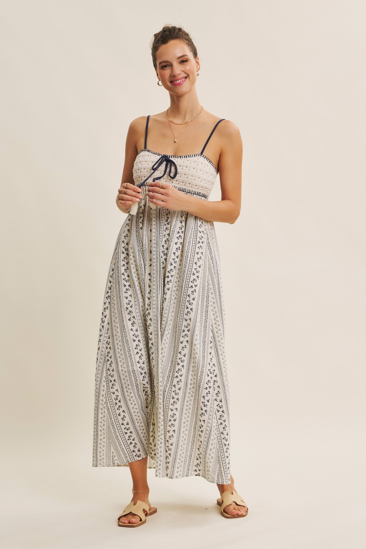 woman wearing a light beige striped maxi dress with spaghetti straps and a drawstring detail