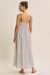 woman wearing a back view of a long white and navy patterned maxi dress with thin straps