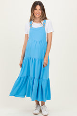 woman wearing a blue maternity sundress with tiered ruffle detail and buttons, showing her baby bump