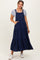 woman wearing a navy blue tiered maternity dress with button details and pockets, styled with a gray t-shirt underneath